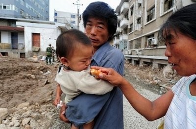 A woman offers a child something to eat amid the rubble of landslides that have devastated the northwestern Chinese town of Zhouqu. AFP A woman offers a child something to eat amid the rubble of landslides that have devastated the northwestern Chinese town of Zhouqu. AFP