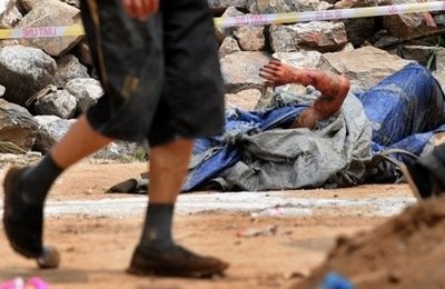 A man walks past the decomposing body of a mudslide victim in Zhouqu. A man walks past the decomposing body of a mudslide victim in Zhouqu.