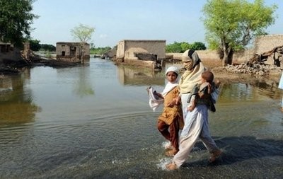 A Pakistani flood survivor wades through water with her childern at Shah Jamal village in Punjab province. A Pakistani flood survivor wades through water with her childern at Shah Jamal village in Punjab province.
