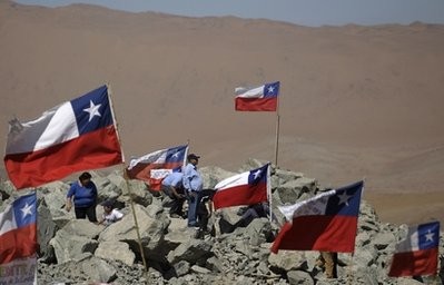 Relatives of 33 miners trapped alive in the San Jose mine stand among Chilean flags outside the mine in Copiapo, Chile, Sunday Aug. 29, 2010. Relatives of 33 miners trapped alive in the San Jose mine stand among Chilean flags outside the mine in Copiapo, Chile, Sunday Aug. 29, 2010.