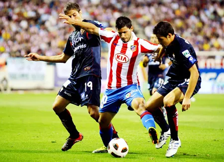 Sergio Kun Aguero (áo đỏ) vượt qua hậu vệ và tiền vệ của Sporting Gijon. Sergio Kun Aguero (áo đỏ) vượt qua hậu vệ và tiền vệ của Sporting Gijon.