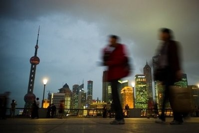 Pedestrians pass in front of the Shanghai skyline. AFP Pedestrians pass in front of the Shanghai skyline. AFP