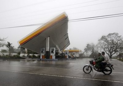 Motorists drive past a filling station which was toppled by typhoon Megi (local name 'Juan') Monday Oct.18, 2010 at Cauayan, Isabelaprovince in northeastern Philippines Motorists drive past a filling station which was toppled by typhoon Megi (local name 'Juan') Monday Oct.18, 2010 at Cauayan, Isabelaprovince in northeastern Philippines