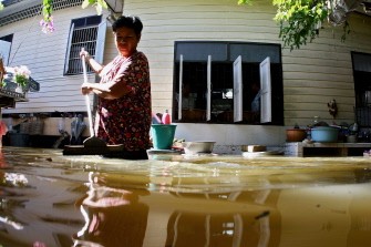 A woman stands in flood water outside her house in Bangkok on october 24, 2010. AFP A woman stands in flood water outside her house in Bangkok on october 24, 2010. AFP