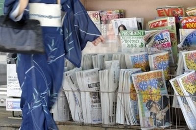 A woman passes in front of a newspaper stand in central Tokyo. A woman passes in front of a newspaper stand in central Tokyo.
