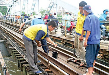 Workers examine the track after a barge hit into the Binh Loi Bridge in HCMC (Photo: SGGP) Workers examine the track after a barge hit into the Binh Loi Bridge in HCMC (Photo: SGGP)