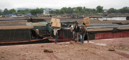Cửu vạn đang vận chuyển hàng lậu xuống thuyền ở Móng Cái. Ảnh: Q.KHÁNH