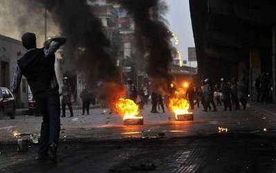 AFP - Egyptian riot police gather near burning tires as a demonstrator throws an object towards them during a protest in Cairo. AFP - Egyptian riot police gather near burning tires as a demonstrator throws an object towards them during a protest in Cairo.