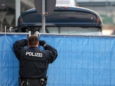 AFP - A German policeman peers through a fence behind which is hidden a US military bus. AFP - A German policeman peers through a fence behind which is hidden a US military bus.