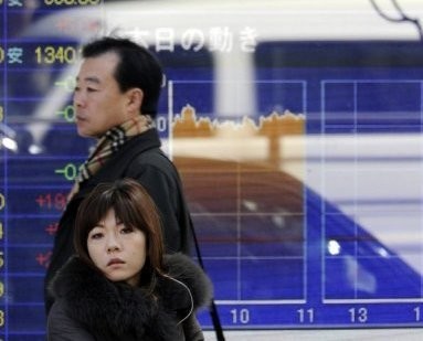 Pedestrians are seen in front of a share price board in Tokyo. Pedestrians are seen in front of a share price board in Tokyo.