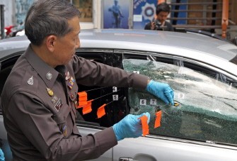 AFP - A Thai policeman investigates the bullet-damaged car of Pracha Prasopdee AFP - A Thai policeman investigates the bullet-damaged car of Pracha Prasopdee