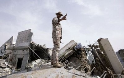 Picture taken on a government guided tour. A Libyan soldier stands on top of a destroyed building in Tripoli as NATO warplanes pounded the Libyan capital Picture taken on a government guided tour. A Libyan soldier stands on top of a destroyed building in Tripoli as NATO warplanes pounded the Libyan capital