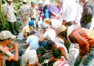People gather on a road on Dak Lak Province to pick golden metal on rocks People gather on a road on Dak Lak Province to pick golden metal on rocks