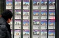 A man walks past the window of a real estate office advertising property for sale … A man walks past the window of a real estate office advertising property for sale …