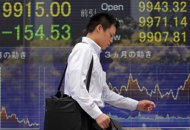 A man walks in front of the electronic stock board of a securities firm in Tokyo, … A man walks in front of the electronic stock board of a securities firm in Tokyo, …