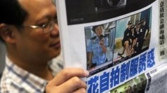 A man reads a local newspaper in Hong Kong featuring front page photos of police women posing in controversial poses A man reads a local newspaper in Hong Kong featuring front page photos of police women posing in controversial poses
