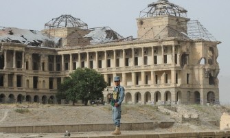 An Afghan policeman stands guard during the funeral of Uruzgan lawmaker Mohammed Ashim Watanwal near Darulaman palace, seen at rear, in Kabul on July 18, 2011. An Afghan policeman stands guard during the funeral of Uruzgan lawmaker Mohammed Ashim Watanwal near Darulaman palace, seen at rear, in Kabul on July 18, 2011.