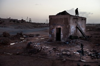 A Libyan rebel fighter stands on the roof of the last check point in Gualish, just a few kilometers away from loyalist forces in Asaba, on July 25, 2011. A Libyan rebel fighter stands on the roof of the last check point in Gualish, just a few kilometers away from loyalist forces in Asaba, on July 25, 2011.