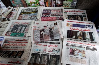Newspapers bearing pictures of former Egyptian president Hosni Mubarak lying on a stretcher inside a cage are displayed on a pavement in Cairo on August 4, 2011 a day after the ousted leader and his sons went on trial for murder