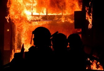 A shop burns as riot police try to contain a large group of people on a main road in Tottenham, north London on August 6, 2011 A shop burns as riot police try to contain a large group of people on a main road in Tottenham, north London on August 6, 2011