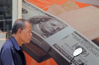 AFP - A pedestrian walks past a poster of US banknotes displayed at currency exchange shop in Bangkok on August 22, 2011 AFP - A pedestrian walks past a poster of US banknotes displayed at currency exchange shop in Bangkok on August 22, 2011