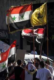 Syrians hold-up their national flag and that of the Lebanese Hezbollah party (R) during a demonstration in support of President Bashar al-Assad in central Damascus on August 23, 2011 Syrians hold-up their national flag and that of the Lebanese Hezbollah party (R) during a demonstration in support of President Bashar al-Assad in central Damascus on August 23, 2011