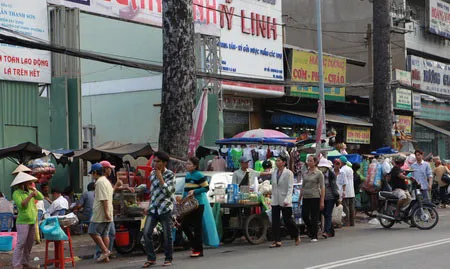 Trên đường Nguyễn Chí Thanh, đoạn trước bệnh viện Chợ Rẫy hình thành một “chợ” trên xe đẩy bán hàng rong chiếm lòng đường, khách bộ hành chỉ còn biết chen ra giữa đường để đi Trên đường Nguyễn Chí Thanh, đoạn trước bệnh viện Chợ Rẫy hình thành một “chợ” trên xe đẩy bán hàng rong chiếm lòng đường, khách bộ hành chỉ còn biết chen ra giữa đường để đi