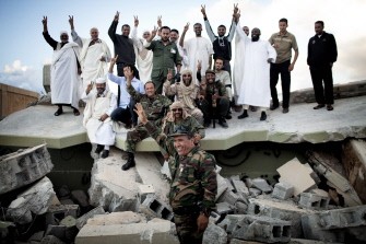 Libyan National Transitional Council (NTC) fighters and civilians celebrate after destroying the walls surrounding former Libyan strongman Moamer Kadhafi's compound Bab al-Aziziya in Tripoli on October 16, 2011 Libyan National Transitional Council (NTC) fighters and civilians celebrate after destroying the walls surrounding former Libyan strongman Moamer Kadhafi's compound Bab al-Aziziya in Tripoli on October 16, 2011