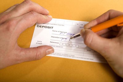 (Image for illustration) Filling in a bank deposit slip