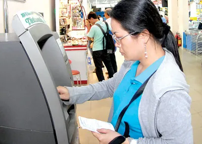 Sử dụng máy ATM tại một siêu thị. Ảnh: Kim Ngân Sử dụng máy ATM tại một siêu thị. Ảnh: Kim Ngân