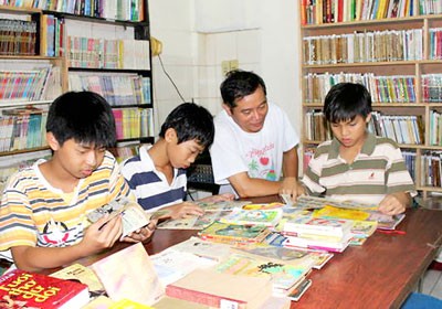 Pham The Cuong ( in white T - shirt ) with young readers at his family library.( photo SGGP ) Pham The Cuong ( in white T - shirt ) with young readers at his family library.( photo SGGP )