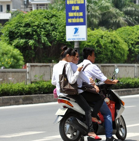 Students disobey traffic rules by not wearing helmets and carrying too many pillion riders on one motorbike Students disobey traffic rules by not wearing helmets and carrying too many pillion riders on one motorbike