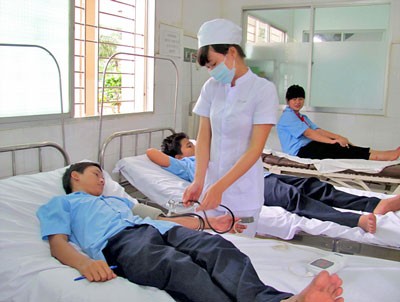 A nurse measures blood pressure of a student who suffered poisoning after consuming the cough medicine (Photo: SGGP) A nurse measures blood pressure of a student who suffered poisoning after consuming the cough medicine (Photo: SGGP)
