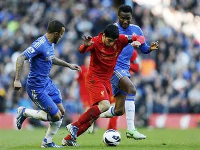 Tiền đạo Luis Suarez (áo đỏ, Liverpool) trong cố gắng đi bóng trước Obi Mikel (phải) và Ryan Bertrand của Chelsea. Tiền đạo Luis Suarez (áo đỏ, Liverpool) trong cố gắng đi bóng trước Obi Mikel (phải) và Ryan Bertrand của Chelsea.