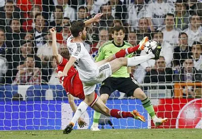 Xabi Alonso (áo trắng) lao về ngăn cú dứt điểm cận thành khá nguy hiểm của Thomas Muller trước cầu môn Casillas. Ảnh: Reuters.