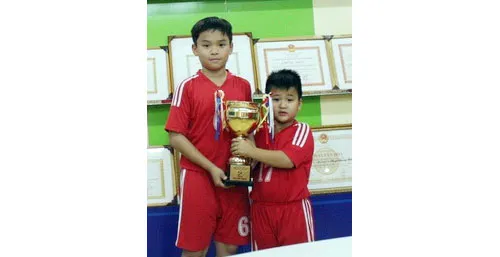 Đội trưởng Nguyễn Thế Vinh và Hoàng Hiệp (phải) bên chiếc cúp vô địch tại phòng lưu niệm của trường.