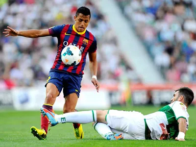 Hậu vệ của Elche truy cản tiền đạo Alexis Sanchez của Barcelona.