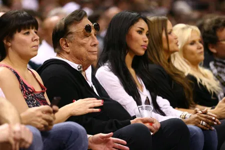 Ông Donald Sterling (đeo kính) và bạn gái V. Stiviano xem một trận bóng rổ năm 2013 ở Texas.