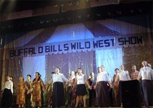 The chorus performs together in a scene on stage (Photo: Bee Shortland) The chorus performs together in a scene on stage (Photo: Bee Shortland)