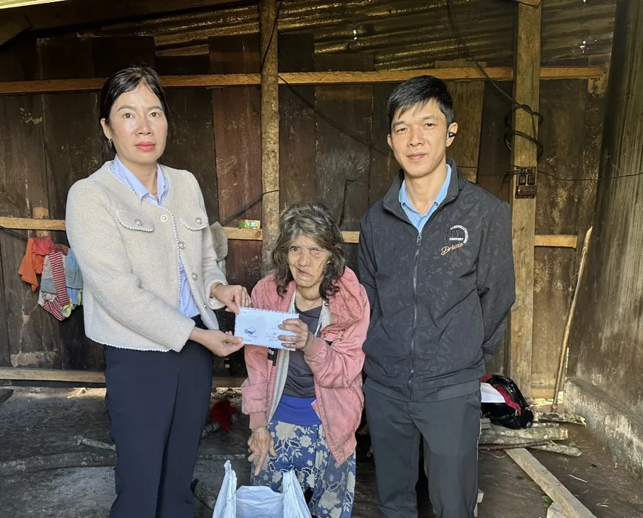 Đại diện UBND xã Đắk Hà và Trường Tiểu học Đắk Hà trao số tiền bạn đọc Báo SGGP hỗ trợ cho cụ bà Y Buah