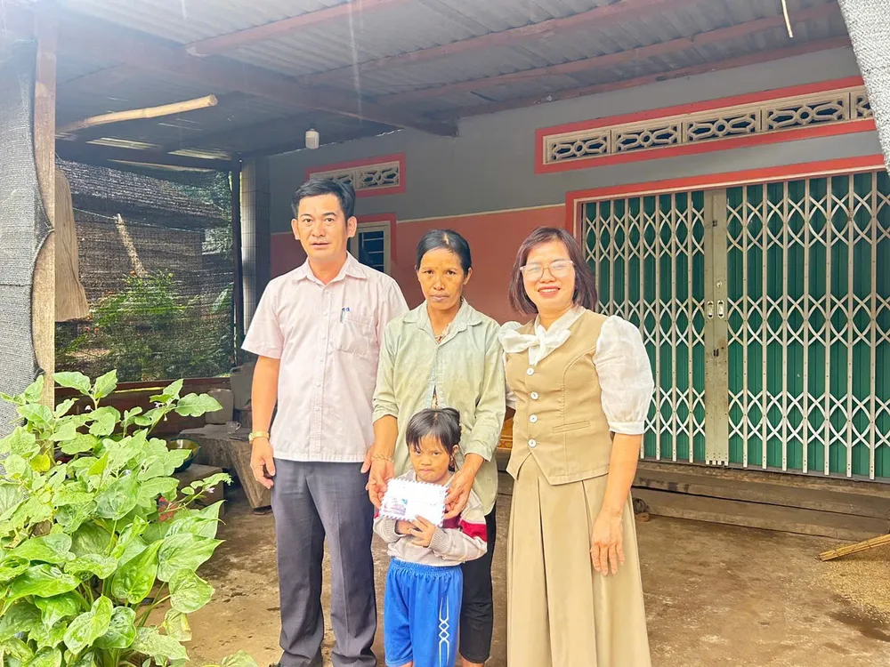 Ông Trần Thanh Hoàng (bên trái), Phó Chủ tịch UBND xã Đăk Tơ Kan thay mặt bạn đọc Báo SGGP trao tiền hỗ trợ đợt 2 cho gia đình cháu Y Lành 5771.jpg