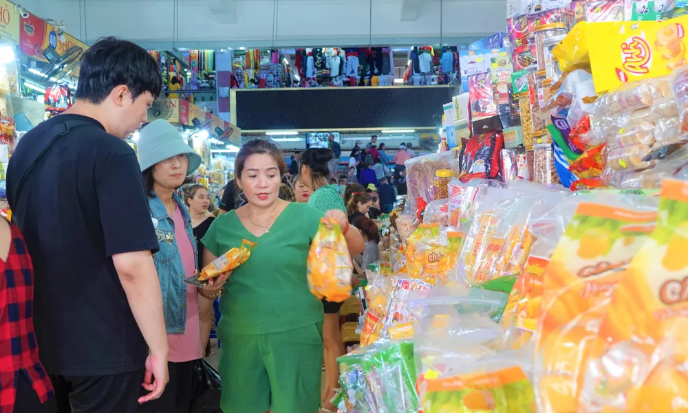 Tiểu thương chợ Hàn đang giới thiệu mặt hàng bánh kẹo cho du khách Hàn Quốc. Ảnh: XUÂN QUỲNH