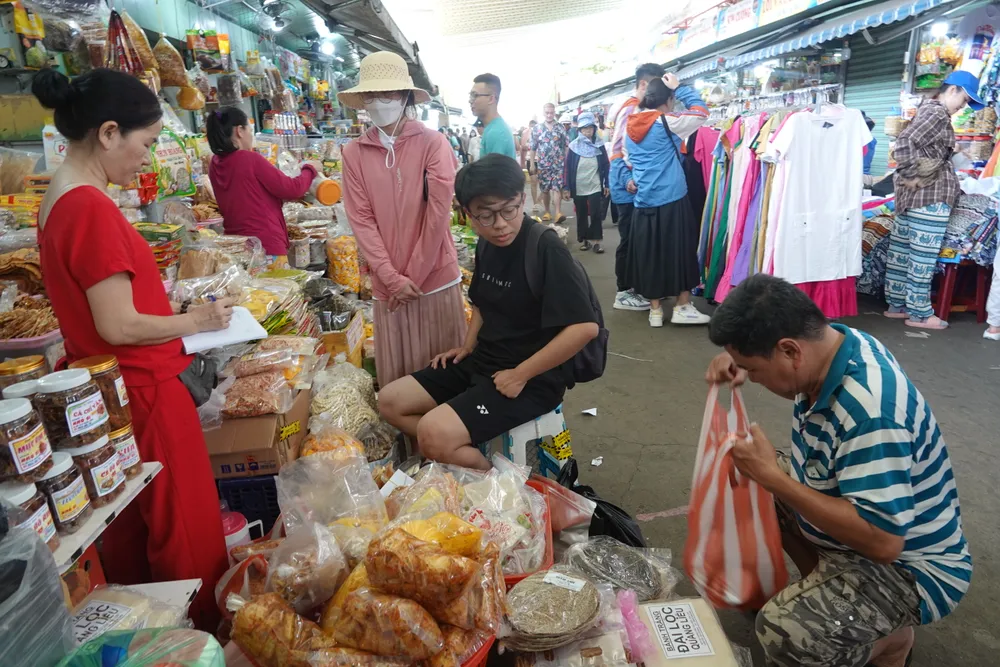 Một gia đình từ TPHCM mua đặc sản tại chợ Cồn trước khi rời TP Đà Nẵng. Ảnh: XUÂN QUỲNH