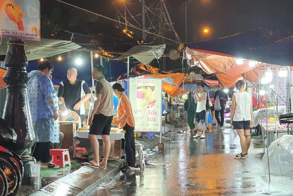 Nhiều du khách vẫn lội bộ tham quan chợ đêm Sơn Trà trong khi trời mưa. Ảnh: XUÂN QUỲNH Nhiều du khách vẫn lội bộ tham quan chợ đêm Sơn Trà trong khi trời mưa. Ảnh: XUÂN QUỲNH