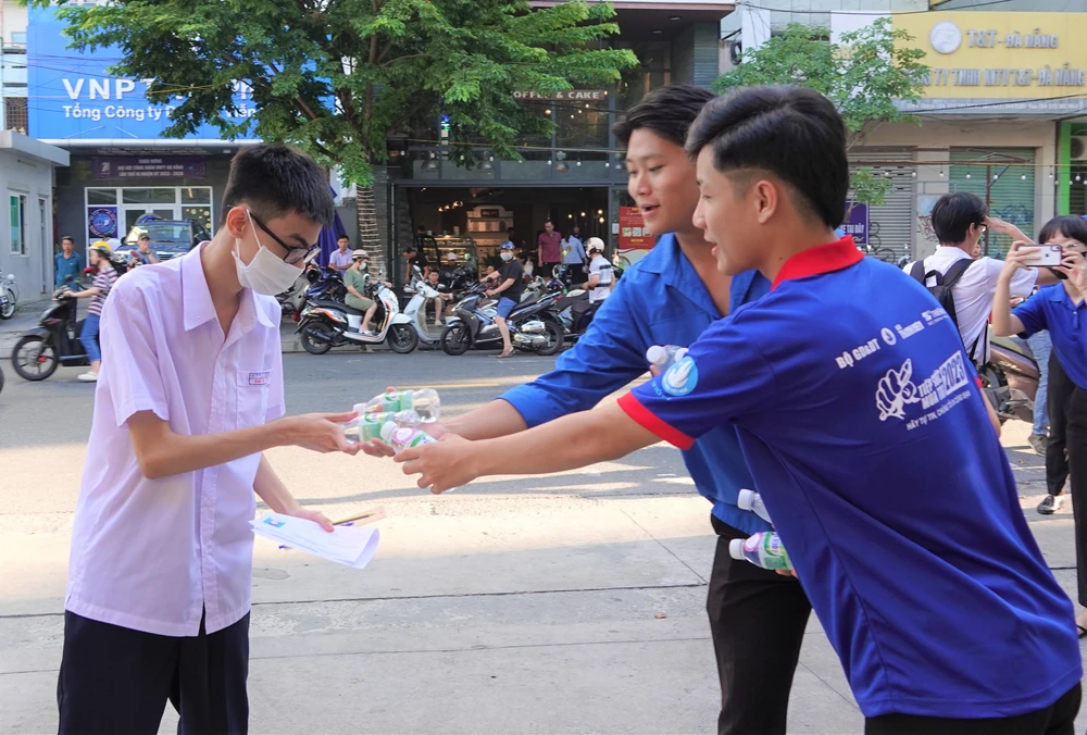 Các tình nguyện viên hỗ trợ tiếp nước cho thí sinh trước điểm trường. Ảnh: XUÂN QUỲNH