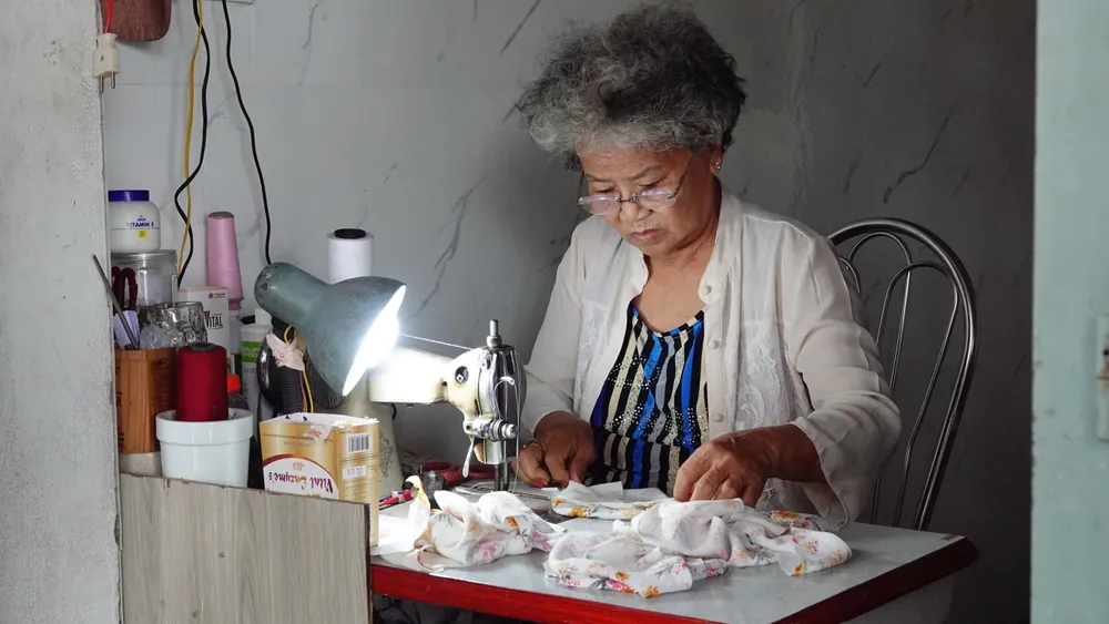 Bà Nguyễn Thị Thuần (71 tuổi, trú tổ 9 phường Hoà Hiệp Nam, quận Liên Chiểu) vừa may vừa kể. Ảnh: XUÂN QUỲNH DSC09487.JPG