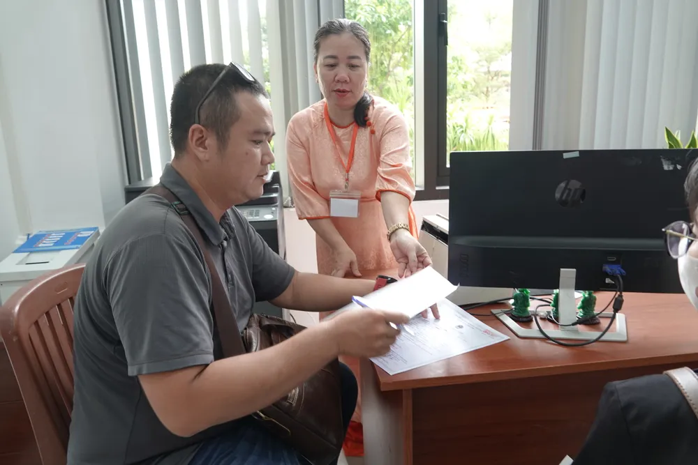 Cán bộ hướng dẫn người dân viết thông tin. Ảnh: XUÂN QUỲNH DSC01996.JPG