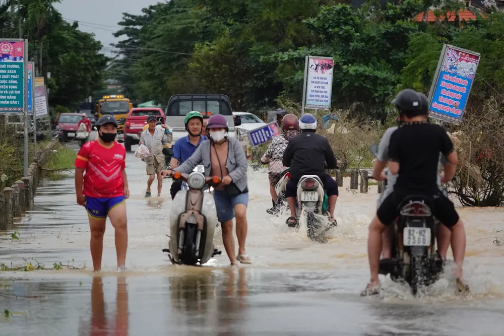 Người dân dắt bộ xe qua đoạn đường vẫn còn ngập nước chiều 31-10. Ảnh: XUÂN QUỲNH DSC07262.JPG