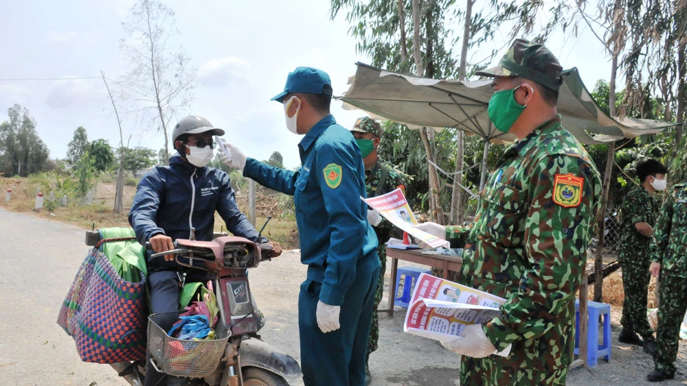 Lực lượng Bộ đội Biên phòng và dân quân tỉnh Đồng Tháp kiểm tra, đo thân nhiệt người dân ở khu vực biên giới