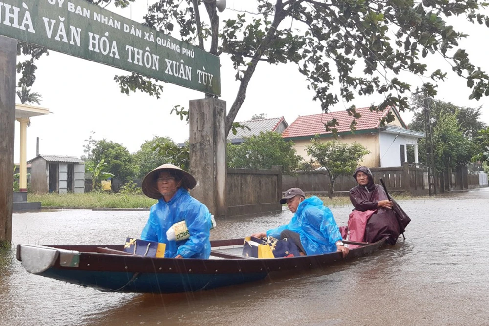 Người dân huyện Quảng Điền, tỉnh Thừa Thiên - Huế di chuyển trên đường ngập lụt, chiều 17-10. Ảnh: VĂN THẮNG